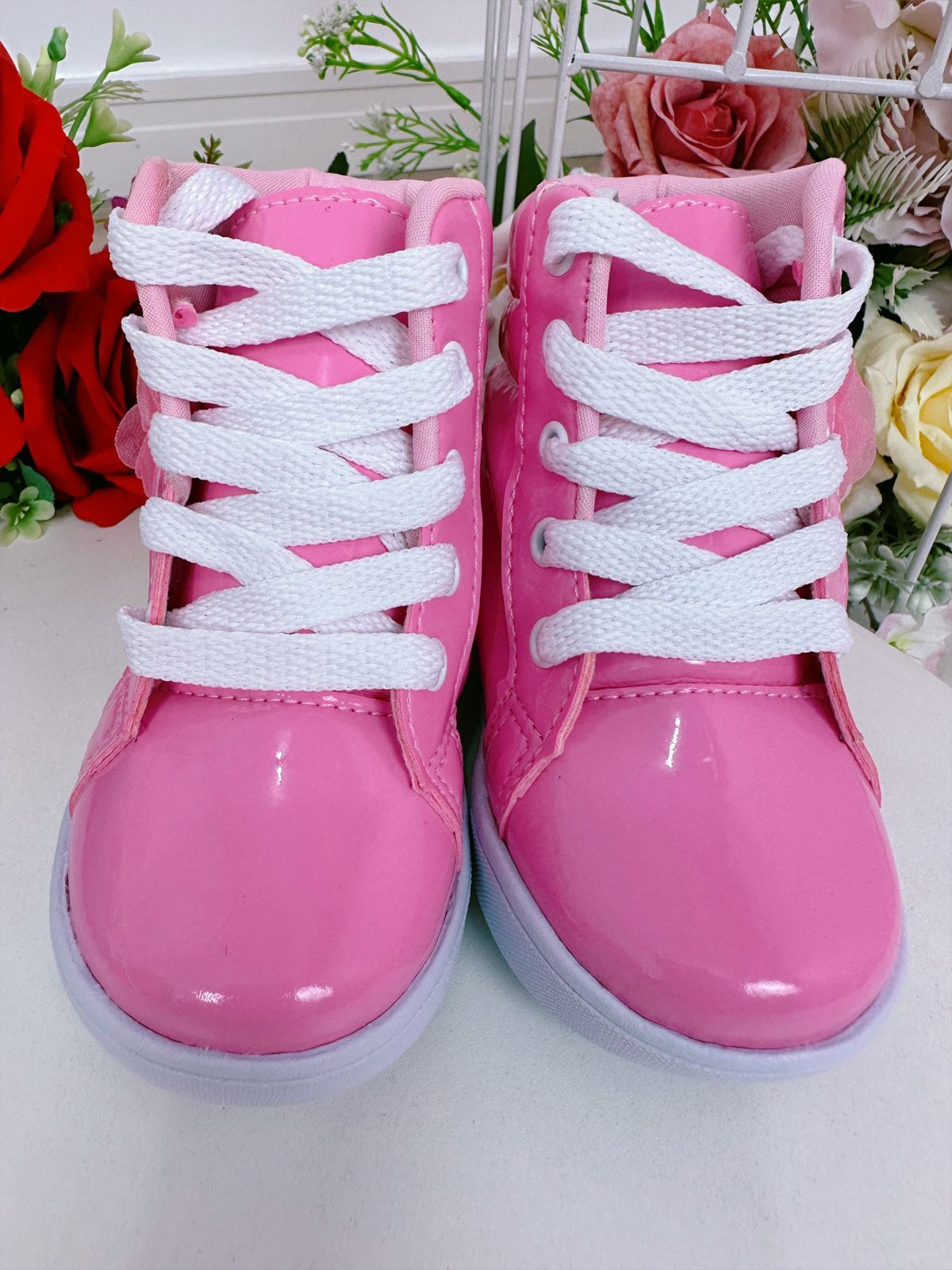 Botines infantiles con flores de mariposa y cordones en color rosa chicle