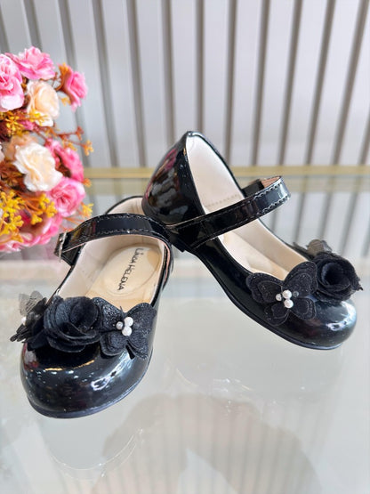 Zapatos infantiles de charol negro con aplique de mariposa y flor