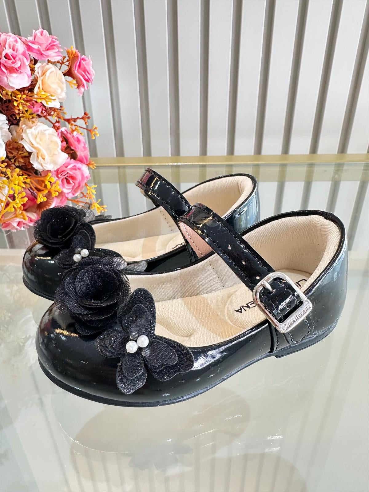 Zapatos infantiles de charol negro con aplique de mariposa y flor