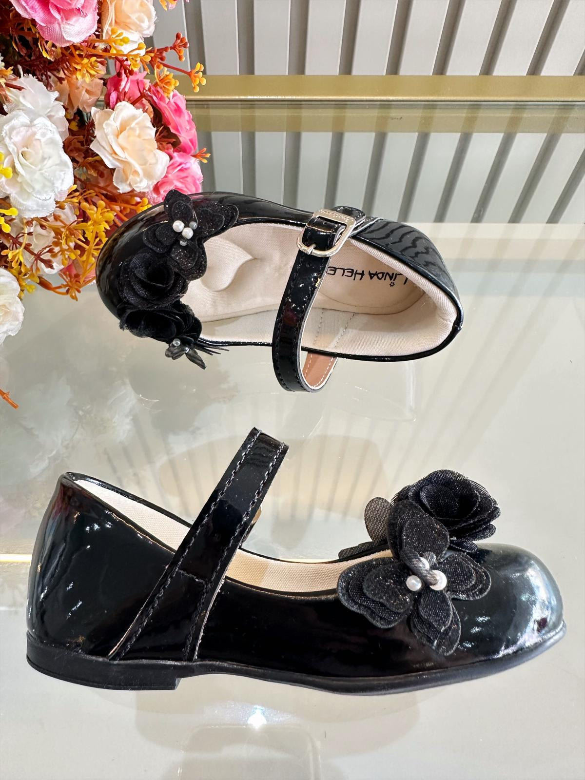 Zapatos infantiles de charol negro con aplique de mariposa y flor
