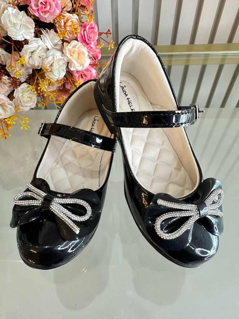 Zapatos infantiles de charol negro con lazo y aplique de pedrería