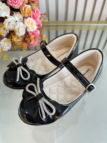 Zapatos infantiles de charol negro con lazo y aplique de pedrería