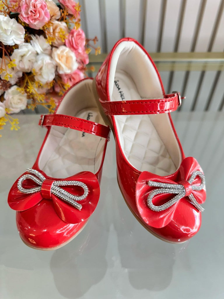 Zapatos infantiles de charol rojo con lazo y aplique de pedrería