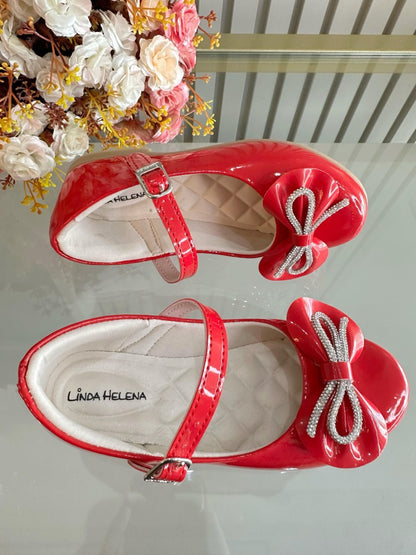 Zapatos infantiles de charol rojo con lazo y aplique de pedrería